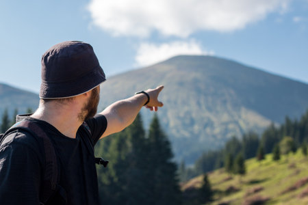 The man with the beard is pointing at the mountain