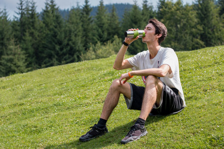 man drinking water on a green meadowの写真素材