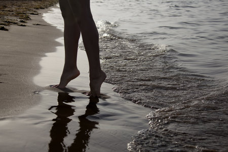 Beautiful female legs on the sandy seashore の写真素材