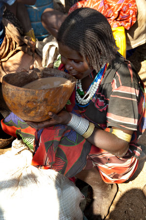 TURMI, OMO VALLEY, ETHIOPIA - NOVEMBER 19, 2011: Unidentified Hamar woman drinks self-made beer at...