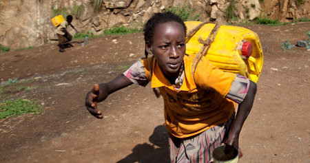 SOUTH OMO - ETHIOPIA - NOVEMBER 19, 2011: Unidentified girl bears the canister with water, in...