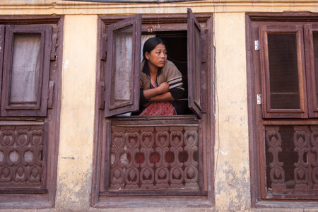 KATHMANDU, NEPAL - NOVEMBER 06, 2006: The woman watch from a home's window on the street of old town on Kathmandu Valley, Nepal.のeditorial素材