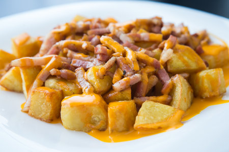 Fried potato recipe with bacon on white plate
