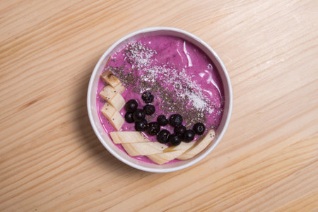 Healthy, acai berry smoothie in a wooden bowl topped with bananas, blueberries, raspberries and blackberriesの写真素材