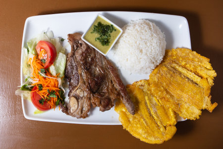 Latin American fry of pork, fried patacon, rice and saladの写真素材
