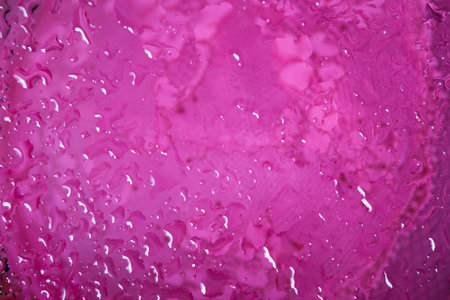 Water drops on glass over textured pink fabric の写真素材
