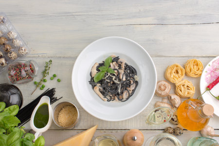 Other ingredients of Italian cuisine whith black pasta with mushrooms and cream  on a white wooden background.の写真素材