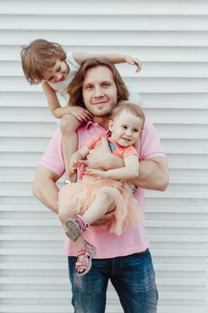Happy family in outdoor park  Dad and two daughters in his arms play happyの写真素材