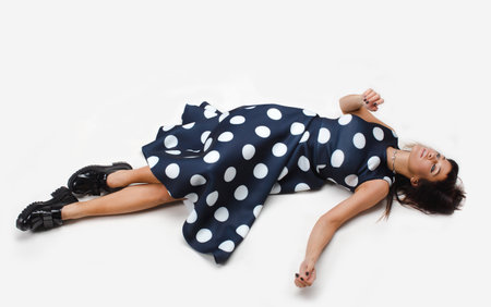 Woman which relaxed sprawled on the floor and looking up in polka dot dressの写真素材