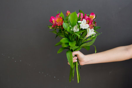 Holding fresh flowers with space on grey wallの写真素材