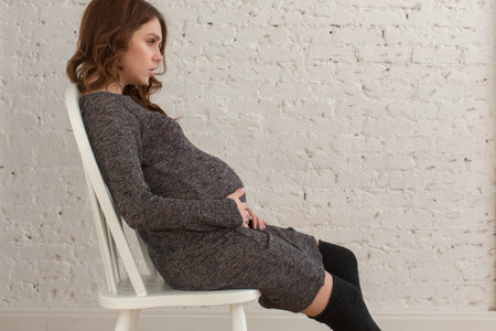 Pregnant female sitting on chair posingの写真素材