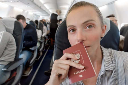 Woman with a passport sitting in airplane interiorの写真素材