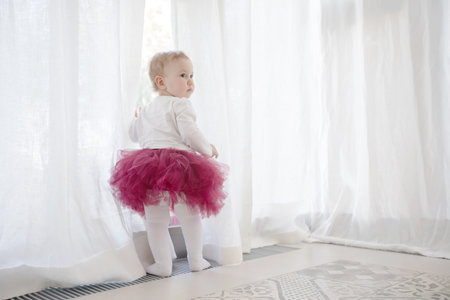 Cute child at window in tutuの写真素材
