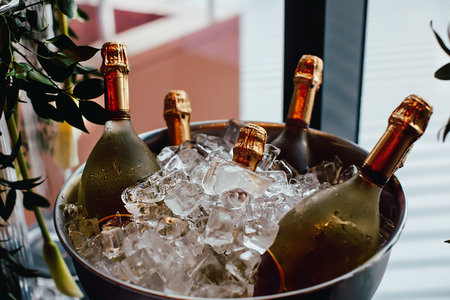 Five wine bottles chill in ice bucket on a buffet tableの写真素材