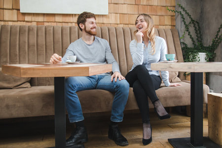 Stylish young man and woman having coffee and chilling happily in cafe.の写真素材