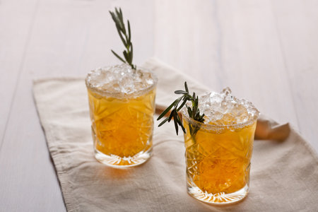 Cooling drinks with ice cubes and a sprig of rosemary on a soft napkinの写真素材