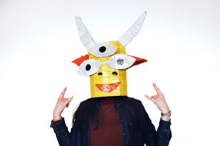 Homemade head of a fairy creature is put on a human monster of cardboard and scooping on a white backgroundの写真素材