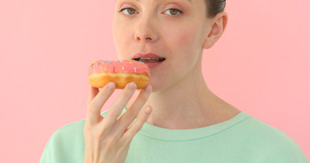 Female mouth bites a loaf. Close-up woman eating a donut , delicious, sweet, sweet tooth at pink backgroundの写真素材