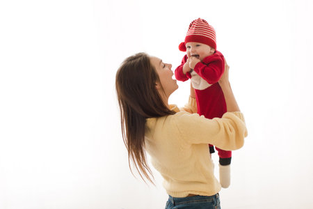 Happy woman carrying little baby in Christmas colorful suit and laughing isolated on white backgroundの写真素材