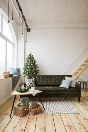 Comfortable sofa standing in middle of stylish room beautifully decorated for Christmas celebration