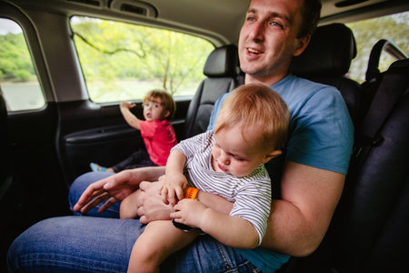 Boy and dad ride in the back seat of a car. Happy father and son sitting together in automobileの写真素材