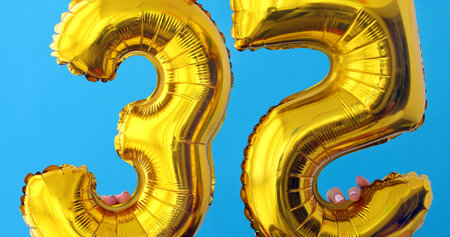 Gold foil number 35 celebration balloon on a blue backgroundの写真素材