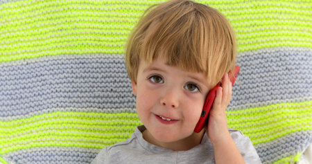 Little child boy speaks smartphone color background
