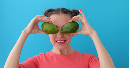 Cheerful Woman Making Avocado Eyes blue background