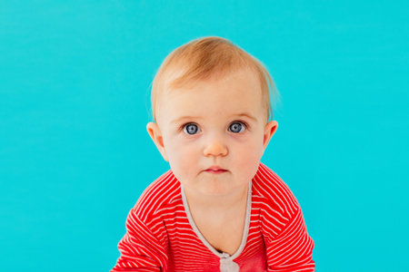 Image of sweet baby, closeup portrait of child, cute toddler with blue eyes on a blue background