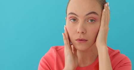 Beautiful young female with sad mood suffering from headache holding hands on head and looking at...
