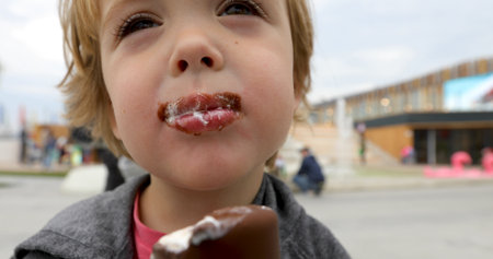 Happy child drinks milk from a cup on pink backgroundの写真素材