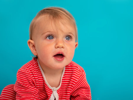 Portrait of a little 11 month old girl smiling on a blue backgroundの写真素材