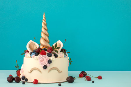 Gourmet unicorn cake with pink and purple buttercream frosting on blue backgroundの写真素材