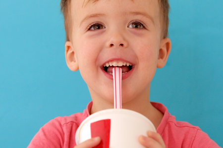 Cute little baby boy drinking milkshake blue backgroundの写真素材