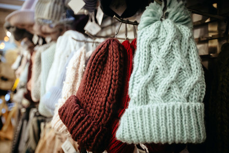 Light blue burgundy knitted hats with pompoms on hangers selling in shopの写真素材