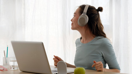 Happy casual beautiful woman working on a laptop and looking away at homeの写真素材