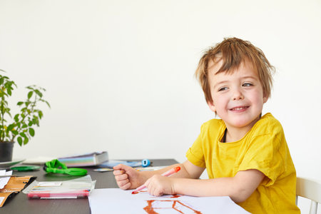 4 years old child Cute boy draws at the table and looks at the camera on a white backgroundの写真素材