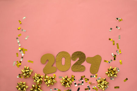 Number 2021 on pink background decorated with pastel and golden starry confetti. New Year...