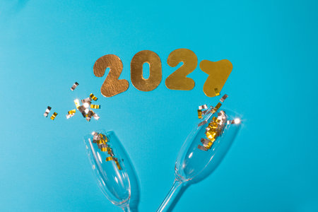Gold numbers 2021 on blue background. New year celebration. Happy New Year 2021 with glasses of...