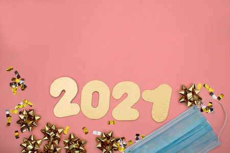 Number 2021 on pink background decorated with golden starry confetti. New Year celebration concept