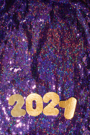 Golden 2021 figures placed on glittering violet background designed for New Year celebration