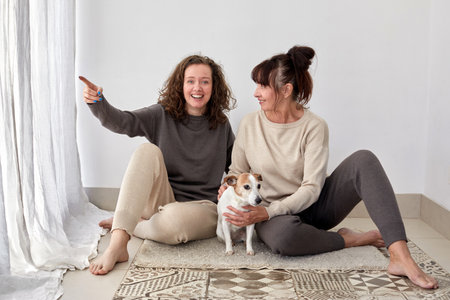 Smiling mother and daughter with dog at homeの写真素材
