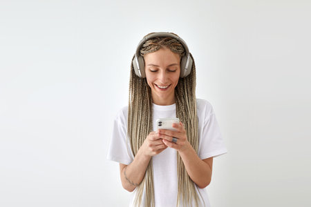 Smiling woman listening to music on smartphone in wireless headphones