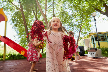 Happy child with pom poms on playground