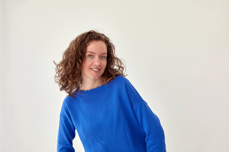 Smiling woman in blue knitted sweater white backgroundの写真素材