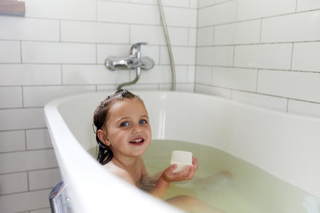 Smiling girl having bath in bathtube bathroom
