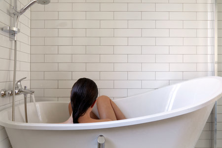 Woman taking bath in bathtub in white bathroomの写真素材