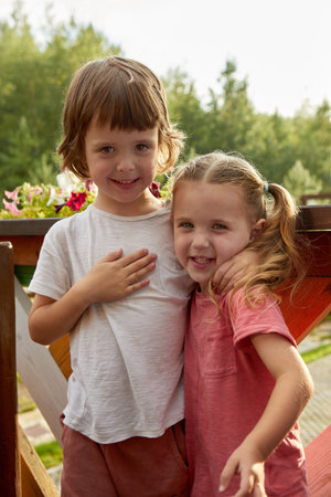 Happy siblings hugging on terrace summer dayの写真素材