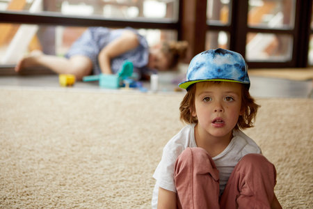 Cute boy sitting on floor in living roomの写真素材