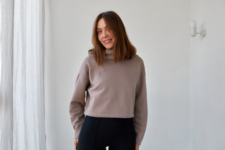 Cheerful woman in hoodie against white wallの写真素材